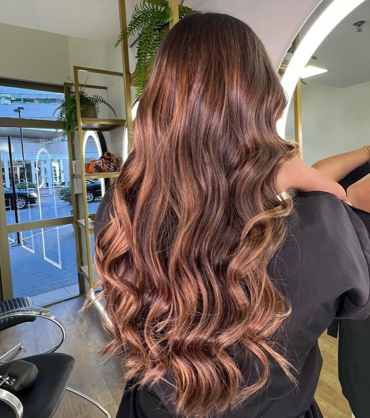 Cabelo longo com reflexos e ondulação, visto de costas no salão